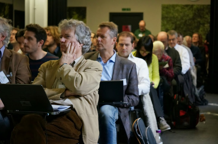 A photo of the room showing all seats taken with standing room only