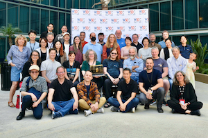 group photo of the W3C Team posing in front of a photo wall with w3c logo for its 30th anniversary